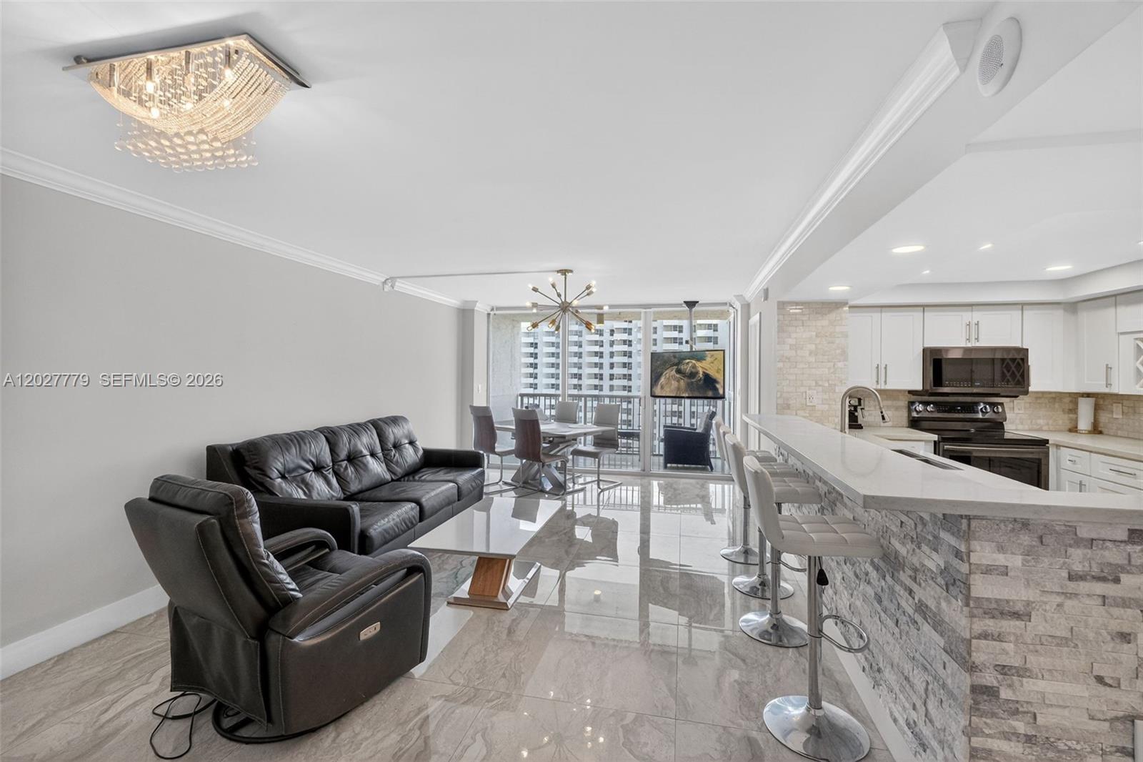 An open-concept living and dining area features tile flooring, a kitchen island, and balcony access — 2655 Collins Ave # 1407, Miami Beach FL 33140, MIAMI BEACH, FL