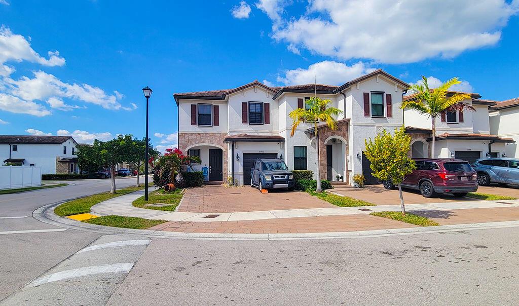 A two-story residential townhouse with a paved driveway, a parked SUV, and palm trees — 10902 W 33rd Way, Hialeah FL 33018, HIALEAH, FL