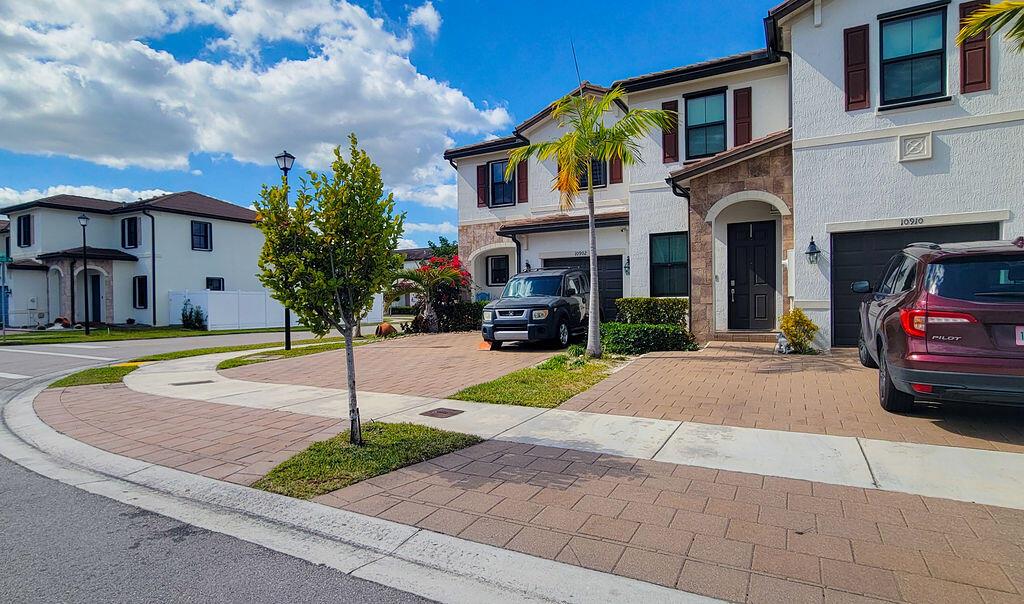 A two-story house with a paved driveway, two parked cars, and a palm tree — 10902 W 33rd Way, Hialeah FL 33018, HIALEAH, FL