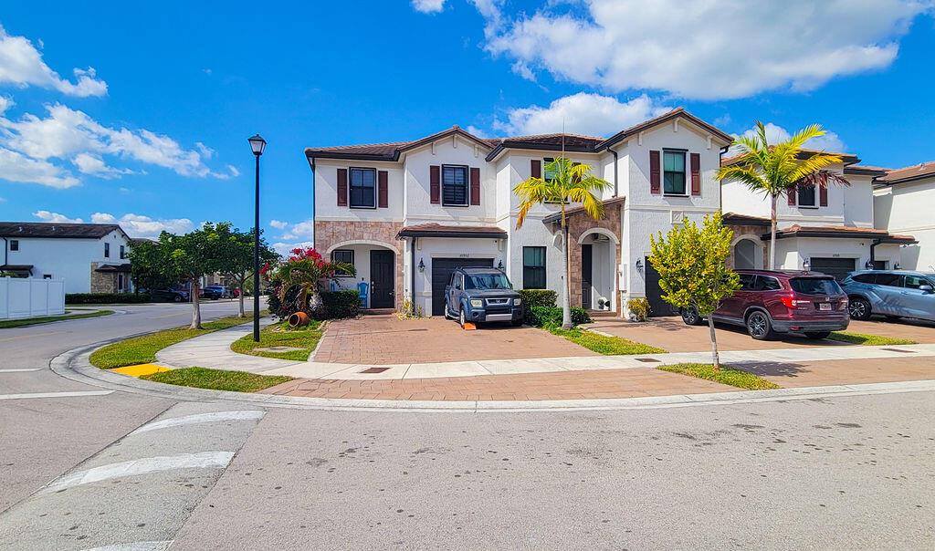 A two-story townhouse with a paved driveway, a garage, and palm trees in the front — 10902 W 33rd Way, Hialeah FL 33018, HIALEAH, FL