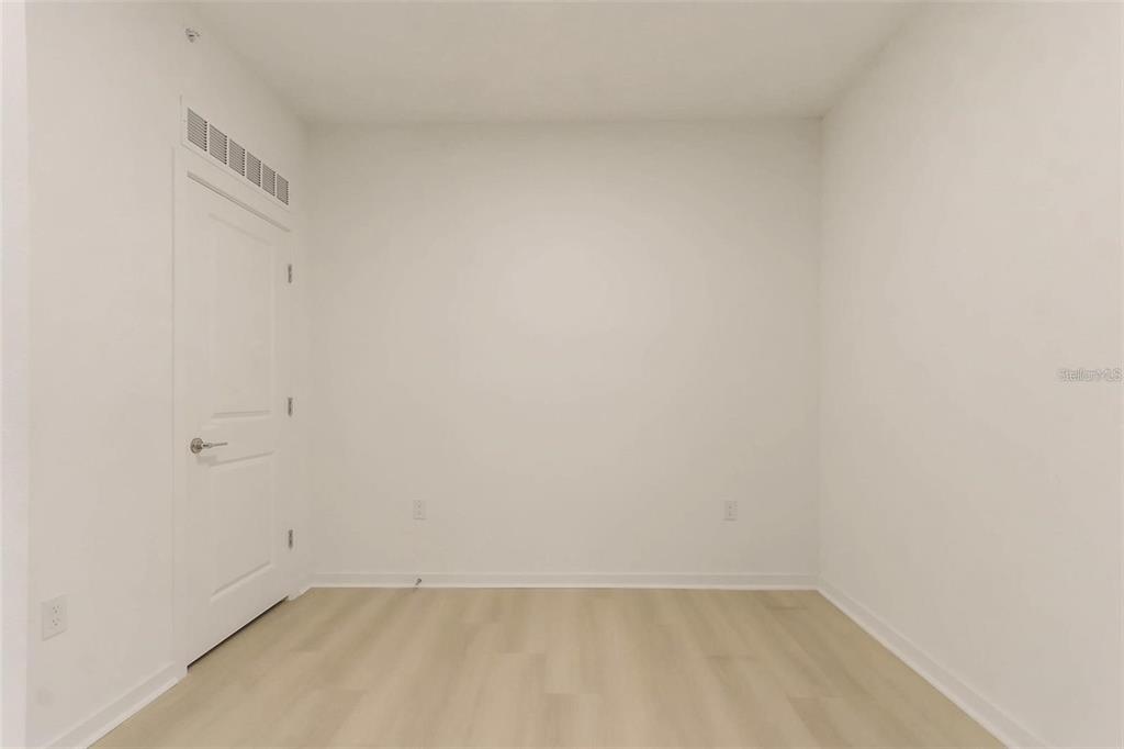 An empty room with white walls, light wood-look flooring, and a single white door — 5587 MILLENIA PARK BLVD UNIT 515, ORLANDO, FL