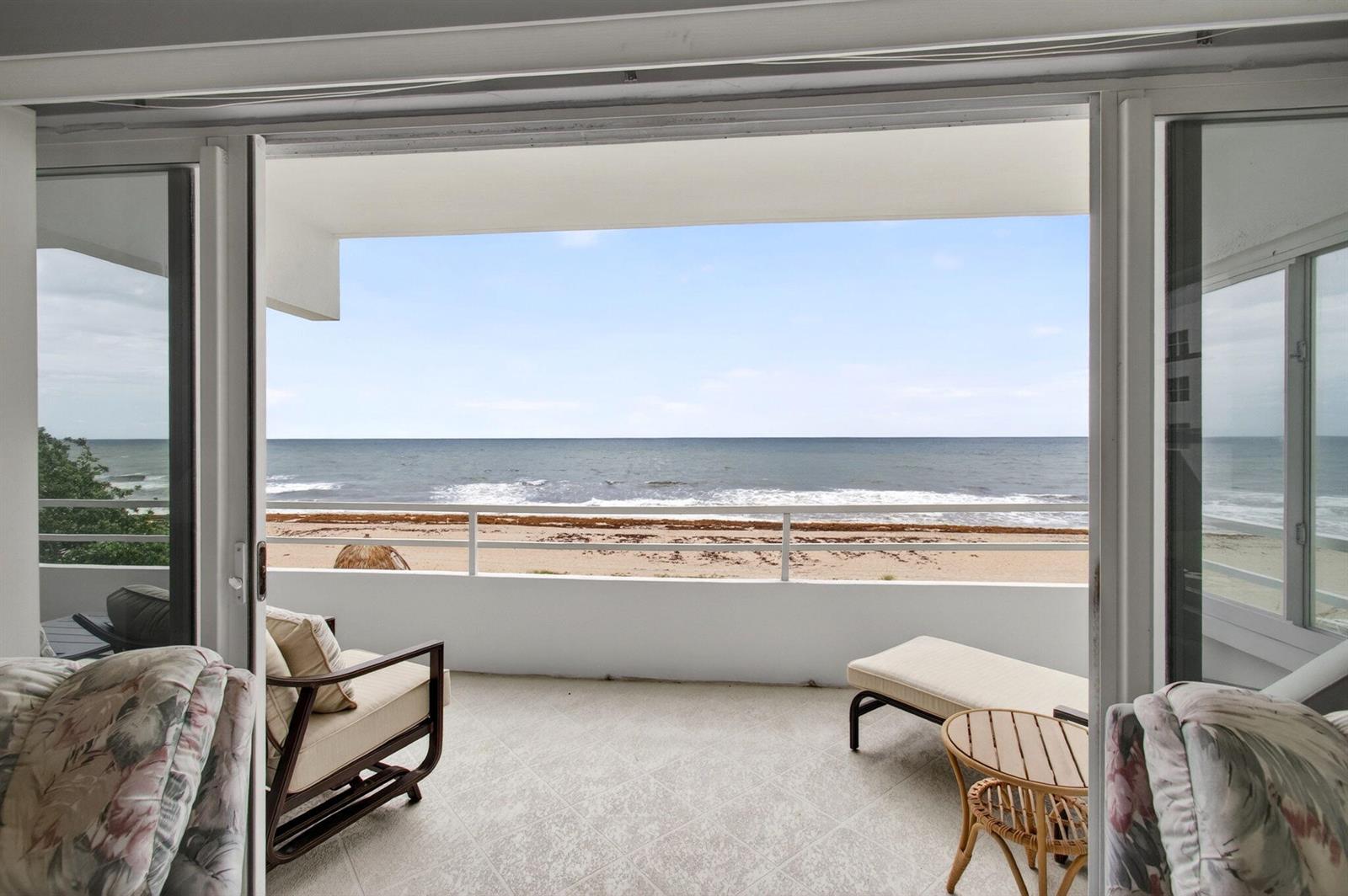 A balcony with tile flooring overlooks the ocean and sandy beach through sliding glass doors — 2701 S Ocean Boulevard # 21, Highland Beach FL 33487, HIGHLAND BEACH, FL