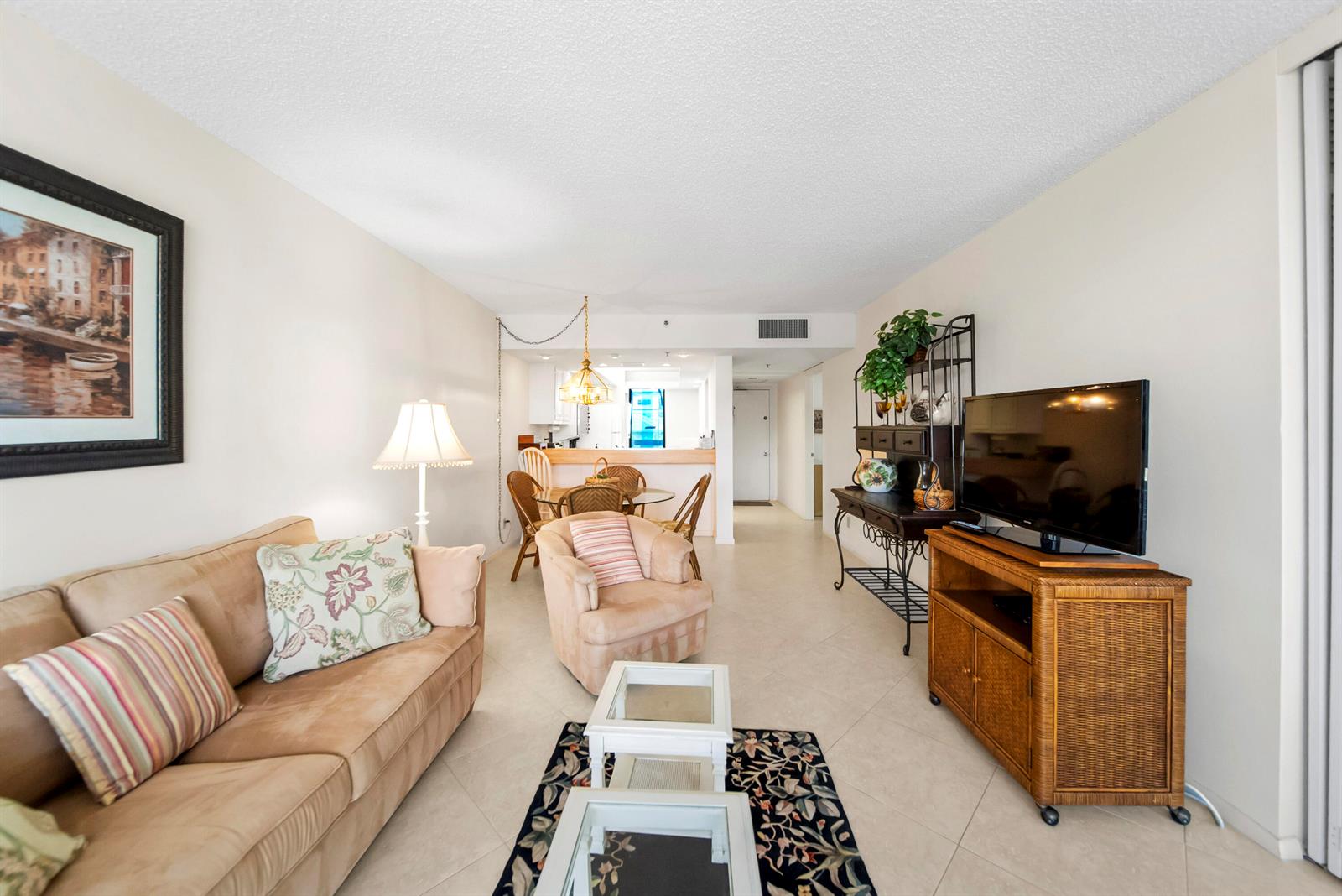 A living room with a beige sofa, armchair, television, and a dining area beyond — 2687 N Ocean Boulevard # 303, Boca Raton FL 33431, BOCA RATON, FL