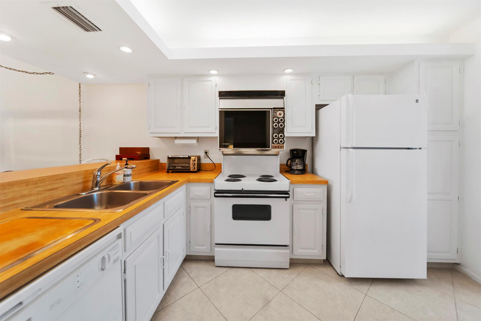 A kitchen features white cabinets, light wood countertops, a white stove, and a white refrigerator — 2687 N Ocean Boulevard # 303, Boca Raton FL 33431, BOCA RATON, FL