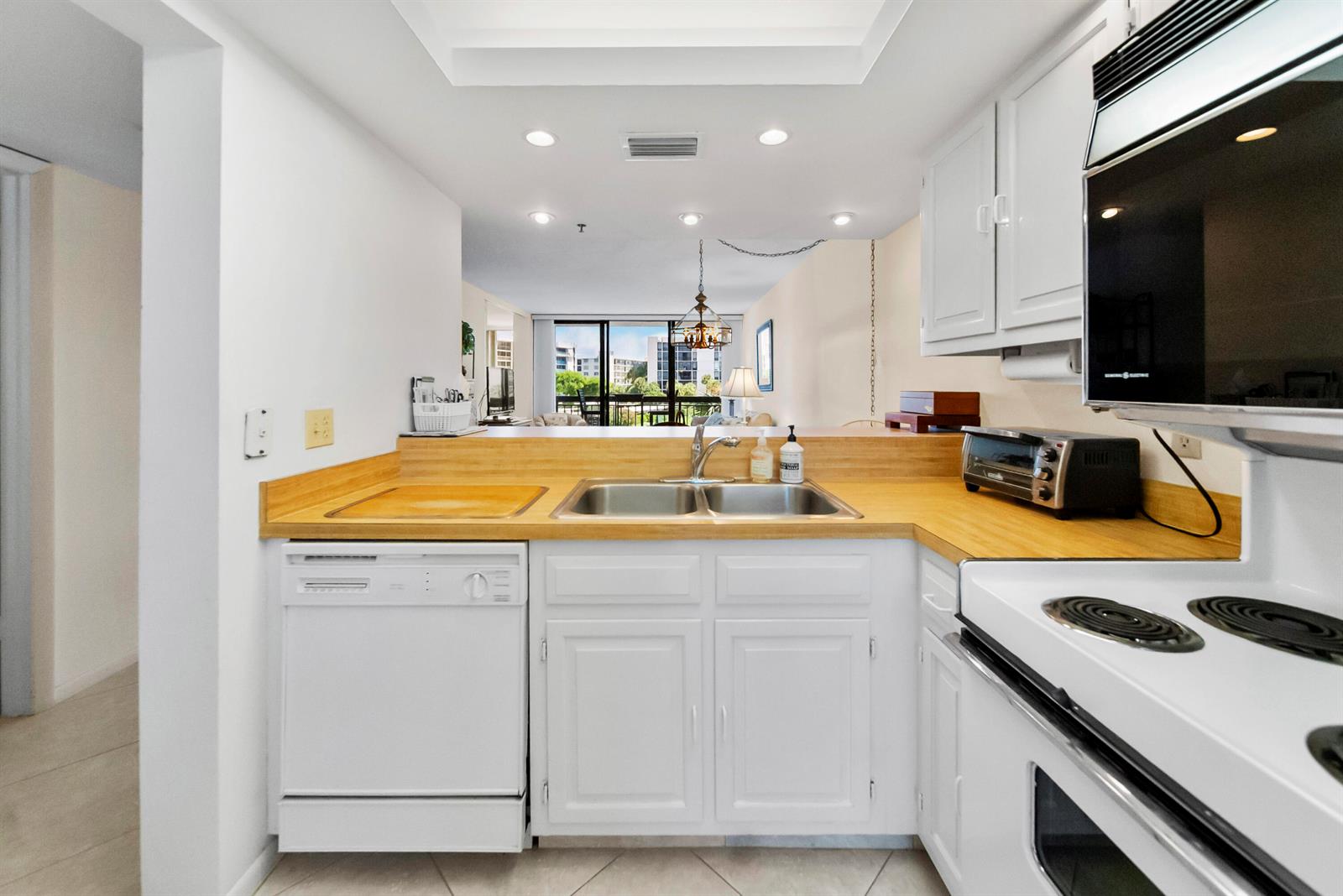 A kitchen features white cabinets, a light wood countertop, a double sink, and white appliances — 2687 N Ocean Boulevard # 303, Boca Raton FL 33431, BOCA RATON, FL