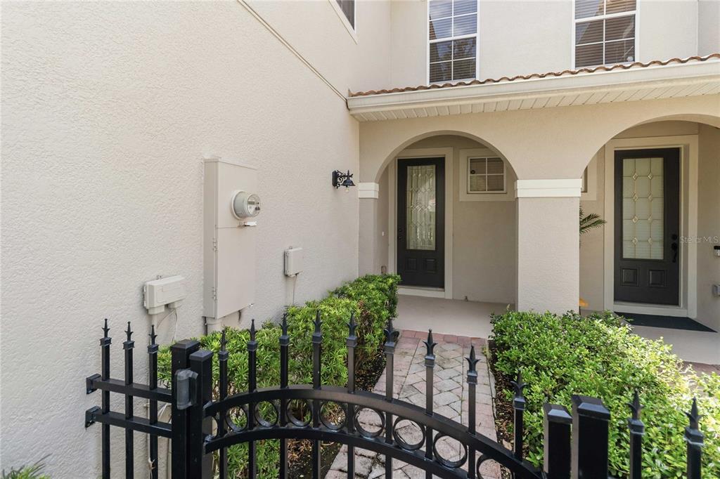 A gated entryway features a stone walkway leading to two dark front doors under arches — 104 CANTERBURY BELL DRIVE, OVIEDO, FL