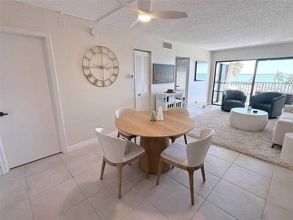 A dining area with a round wooden table and chairs sits adjacent to a living room — 6322 PALMA DEL MAR BOULEVARD S UNIT 213, ST PETERSBURG, FL
