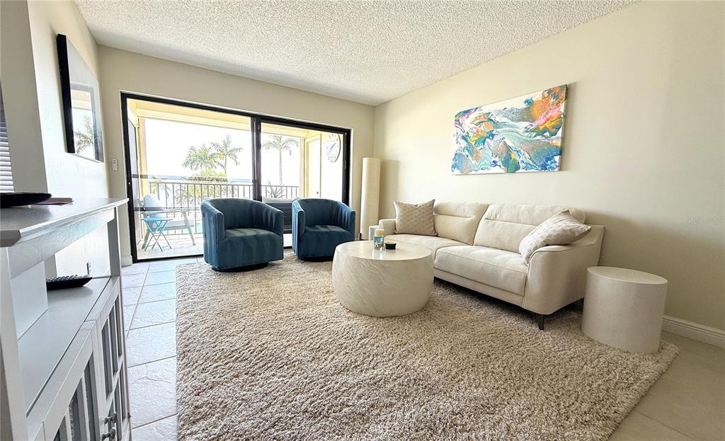 A living room features a beige sofa, two blue armchairs, a round coffee table, and a balcony — 6322 PALMA DEL MAR BOULEVARD S UNIT 213, ST PETERSBURG, FL