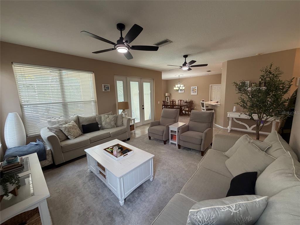 A living room features two sofas, two armchairs, a white coffee table, and ceiling fans — 217 36TH STREET NE, BRADENTON, FL