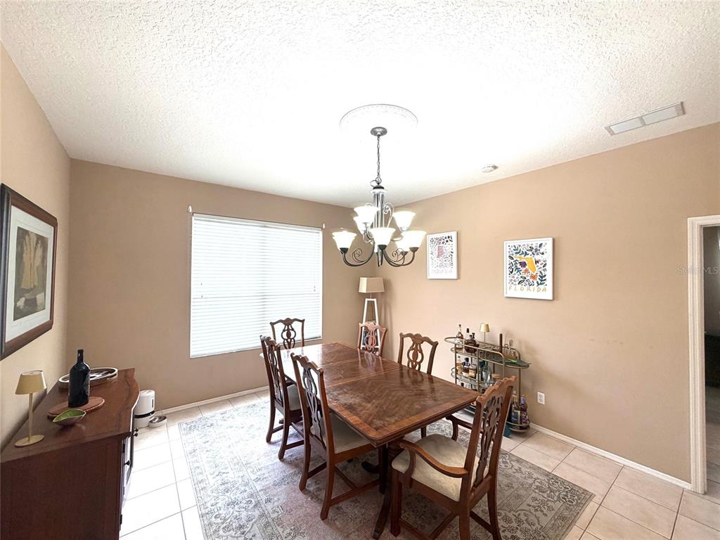A dining room features a wooden table, six chairs, a chandelier, and a bar cart — 217 36TH STREET NE, BRADENTON, FL