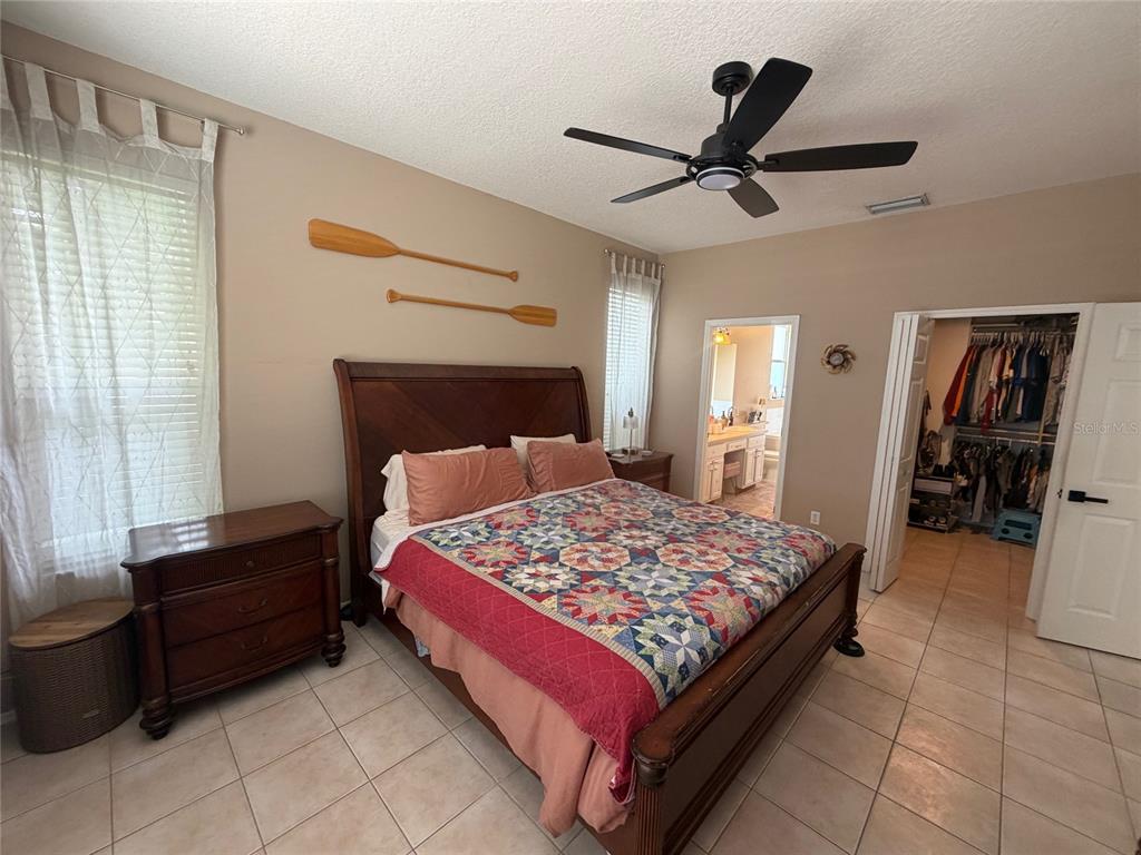 A bedroom features a wooden bed frame, a quilt, two oars on the wall, and tile flooring — 217 36TH STREET NE, BRADENTON, FL