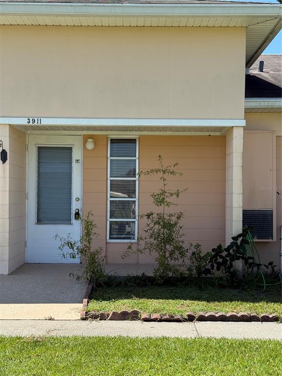 The exterior of a house features a white front door, a window, and a small garden — 3911 CLUB CIRCLE, LAKE WALES, FL