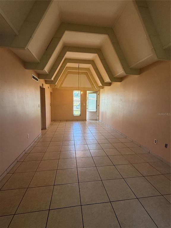 An empty room features a vaulted ceiling, light-colored tile flooring, and a single window — 3911 CLUB CIRCLE, LAKE WALES, FL