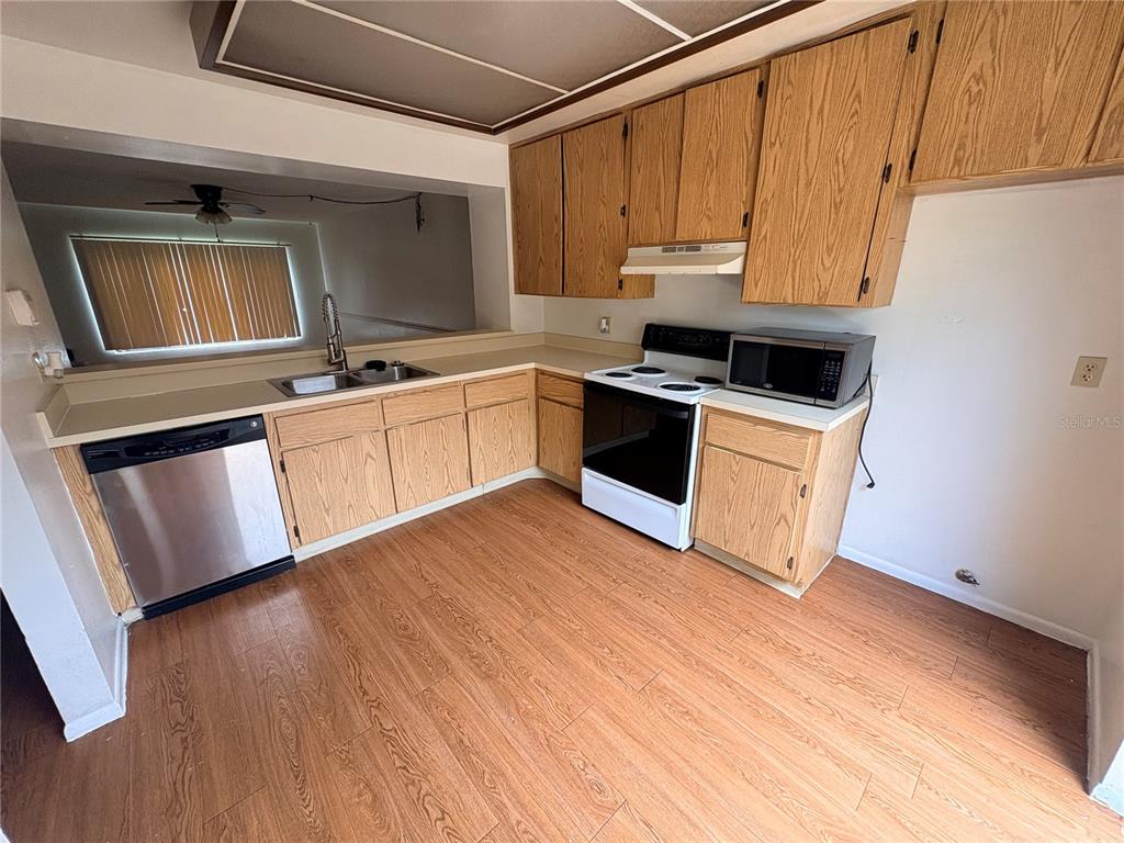 A kitchen features wood cabinets, stainless steel appliances, and wood-look flooring — 7907 TANGERINE DRIVE, TAMPA, FL