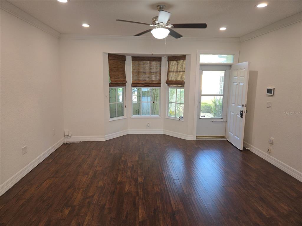 A room with dark wood floors, a bay window with bamboo shades, and a ceiling fan — 2644 SABAL SPRINGS DRIVE UNIT 3, CLEARWATER, FL