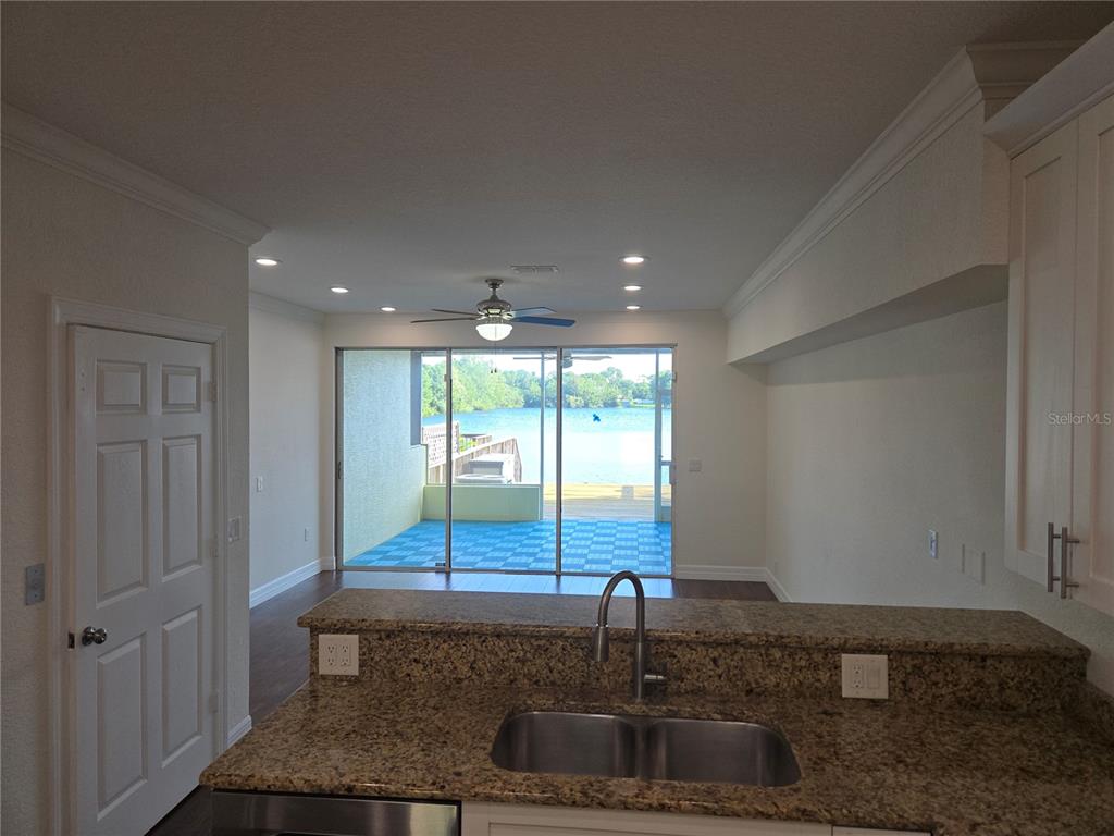 A kitchen with granite countertops overlooks a living area with sliding doors leading to a deck — 2644 SABAL SPRINGS DRIVE UNIT 3, CLEARWATER, FL