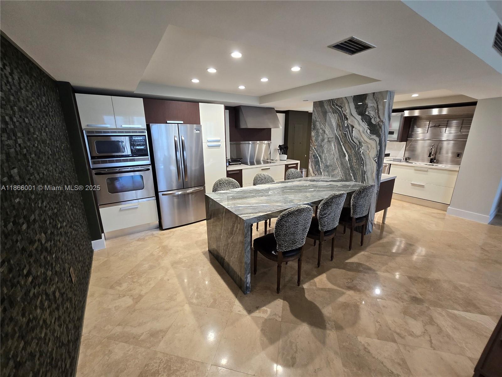 A modern kitchen features a stone waterfall island, stainless steel appliances, and patterned dining chairs — 11113 Biscayne Blvd # 854, Miami FL 33181, MIAMI, FL