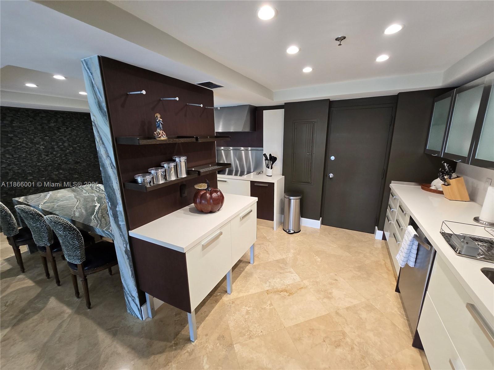 A modern kitchen features white cabinetry, dark wood accents, stone countertops, and tile flooring — 11113 Biscayne Blvd # 854, Miami FL 33181, MIAMI, FL
