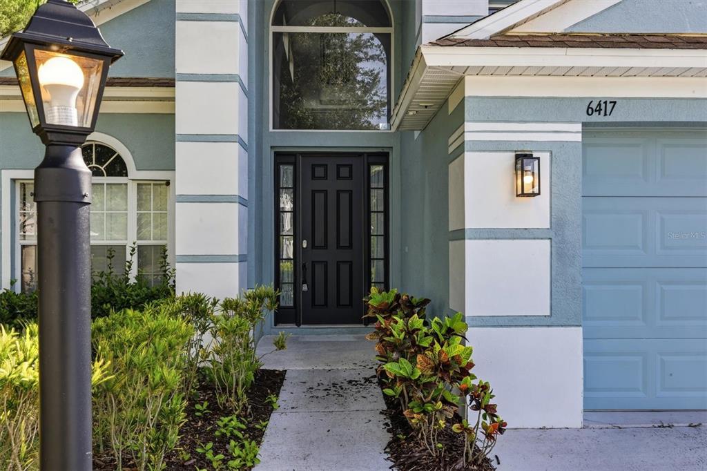 The exterior of a house features a black front door, a garage, and a lamppost — 6417 BLUE GROSBEAK CIRCLE, BRADENTON, FL