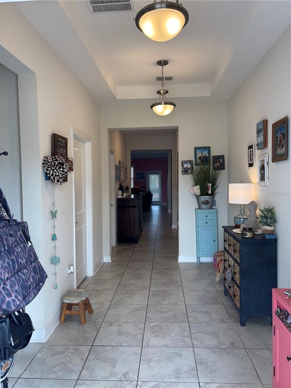A tiled entryway features two hanging light fixtures, a tray ceiling, and various furniture pieces — 4697 FAIRY TALE CIRCLE, KISSIMMEE, FL