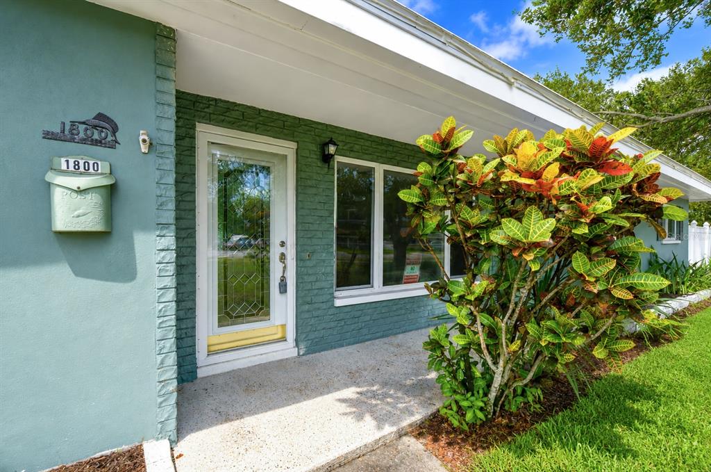 The exterior of a house features a teal brick facade, a front door, and a plant — 1800 DRUID ROAD E, CLEARWATER, FL