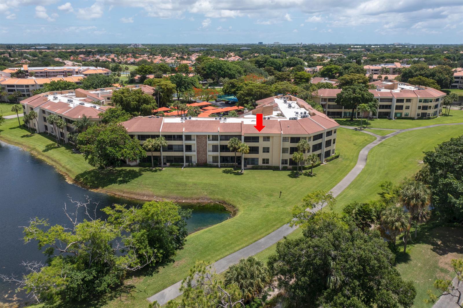 An aerial view shows a multi-story apartment building with a red tile roof near water — 7520 La Paz Boulevard # 104, Boca Raton FL 33433, BOCA RATON, FL