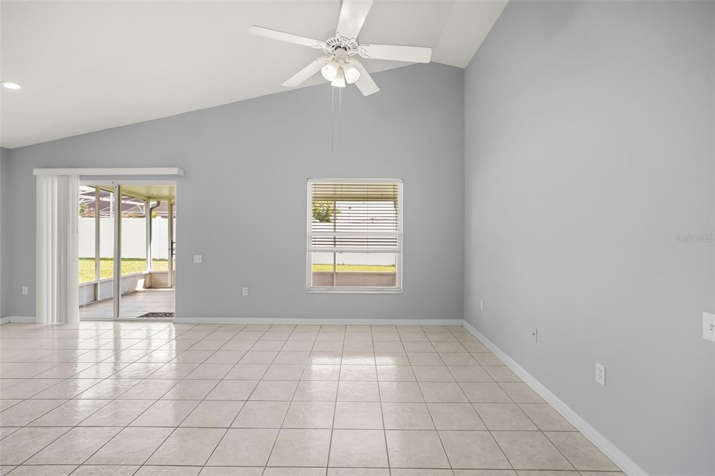 A bright living room with tile floors, a ceiling fan, and a sliding glass door — 3222 WHOOPING CRANE RUN, KISSIMMEE, FL