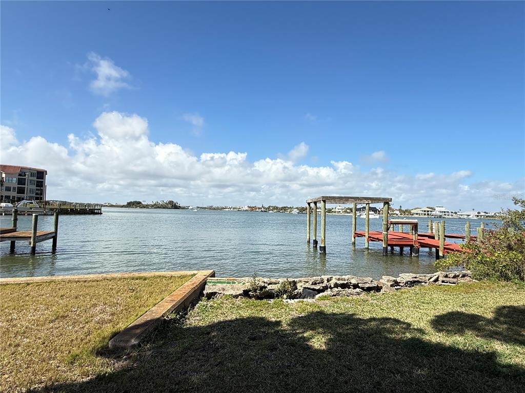 A view of a waterfront property featuring a grassy lawn, stone bulkhead, and wooden docks — 508 S INDIAN RIVER ROAD, NEW SMYRNA BEACH, FL