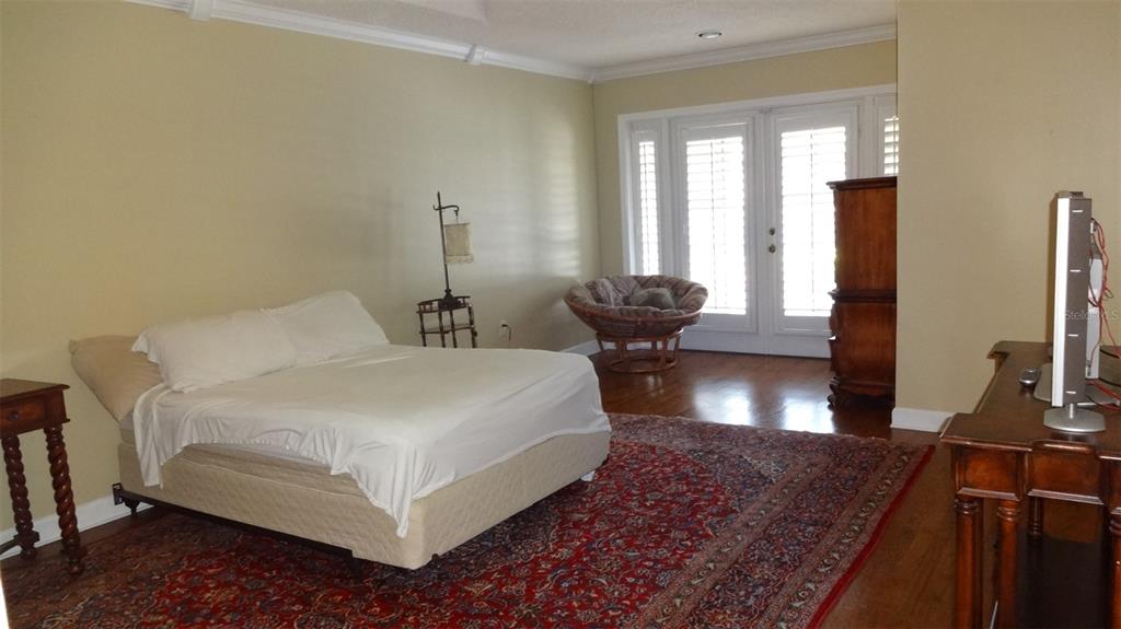 A bedroom with a bed, a red patterned rug, a papasan chair, and French doors — 1144 DELANEY AVENUE UNIT 1144, ORLANDO, FL