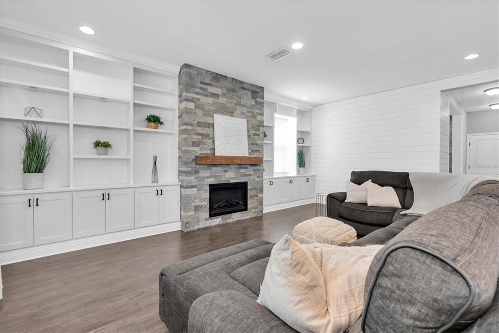 A living room features a stone fireplace, built-in white shelving, and a gray sectional sofa — 12345 TIBBETTS STREET, ODESSA, FL