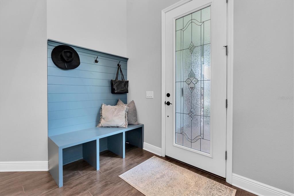 An entryway features a blue shiplap mudroom bench with storage cubbies and a glass-paneled door — 12345 TIBBETTS STREET, ODESSA, FL