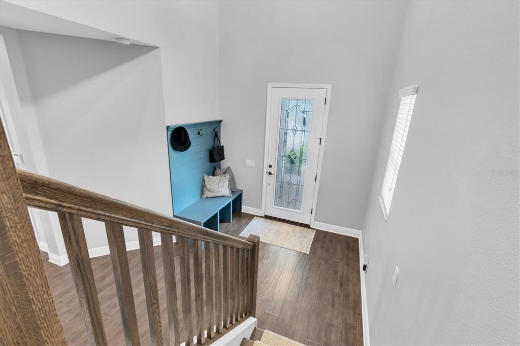 An entryway features a blue built-in bench, wood-look tile flooring, and a staircase with railings — 12345 TIBBETTS STREET, ODESSA, FL