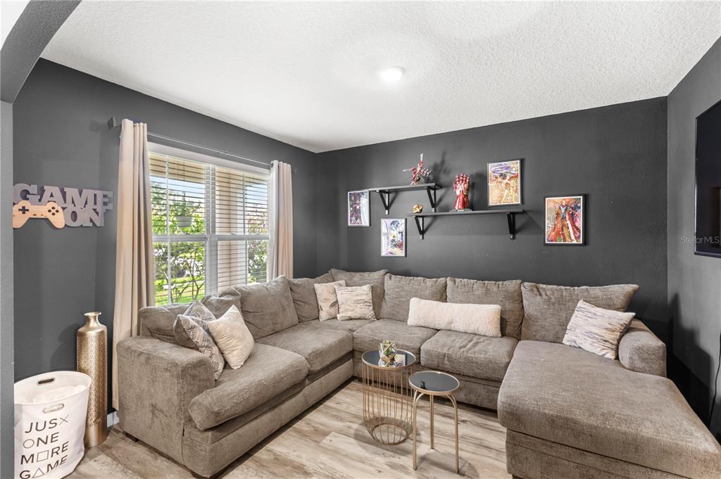 A living room features a large gray sectional sofa, dark accent walls, and floating shelves — 9024 ALBA LANE, KISSIMMEE, FL