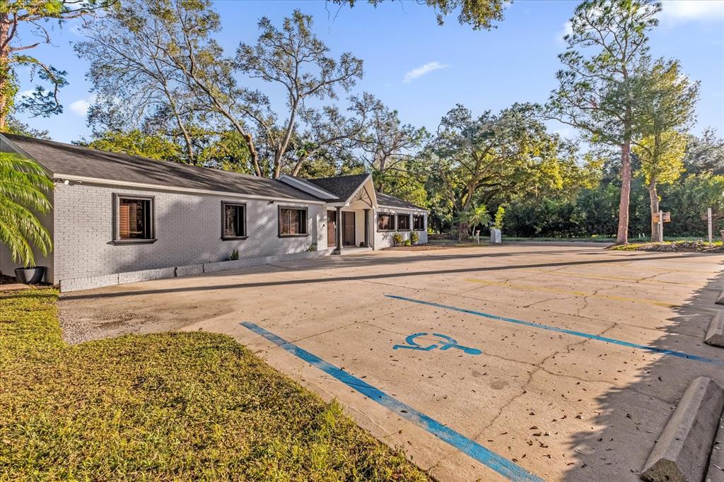 A single-story gray brick building features a large concrete parking lot with a handicap space — 806 E 25TH STREET, SANFORD, FL
