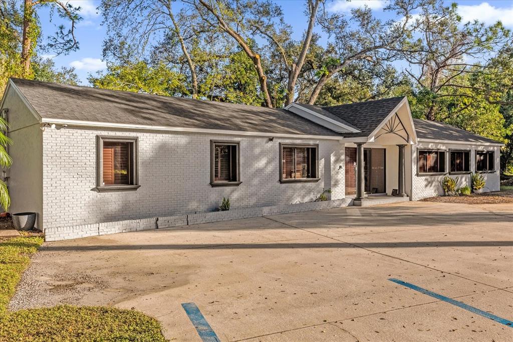A single-story white brick building with a dark shingled roof and a paved parking lot — 806 E 25TH STREET, SANFORD, FL