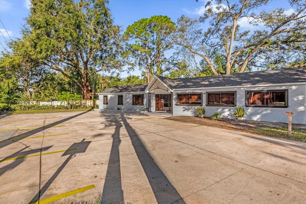 A single-story gray building with a large concrete parking lot and mature trees — 806 E 25TH STREET, SANFORD, FL