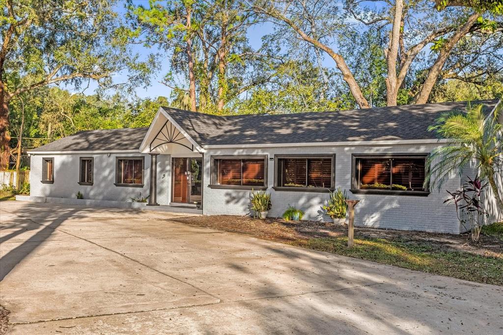 A single-story gray brick building with a gabled entryway and a large concrete driveway — 806 E 25TH STREET, SANFORD, FL