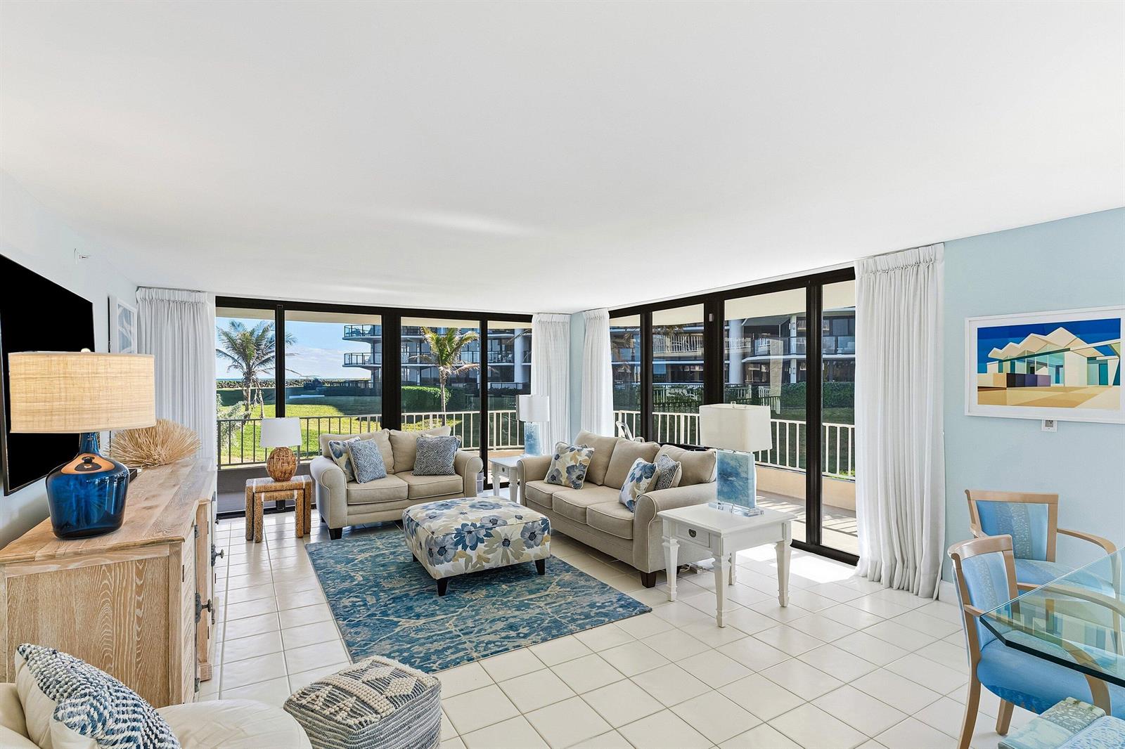 A bright living room features tile floors, two beige sofas, and large sliding glass doors — 3400 S Ocean Boulevard, Palm Beach FL 33480, PALM BEACH, FL