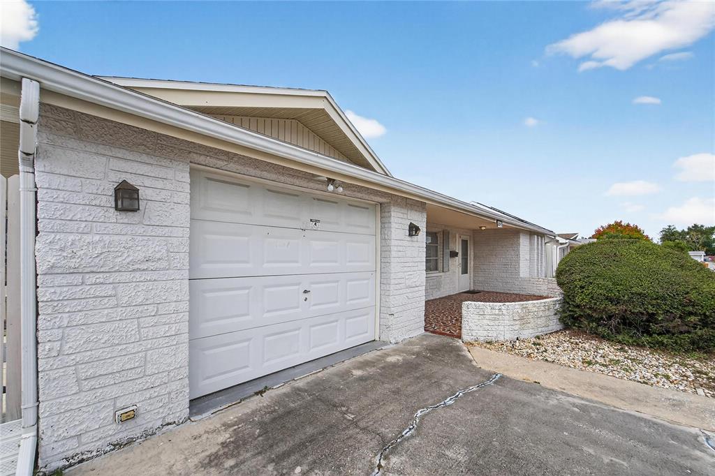 A white brick house features a single-car garage and a small front patio area — 10841 PICCADILLY ROAD, PORT RICHEY, FL