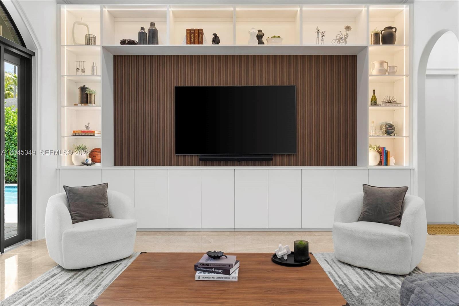 A living room features a wall-mounted television on a wood-slatted panel with built-in shelving — 6874 SW 57th Ter, Miami FL 33143, MIAMI, FL
