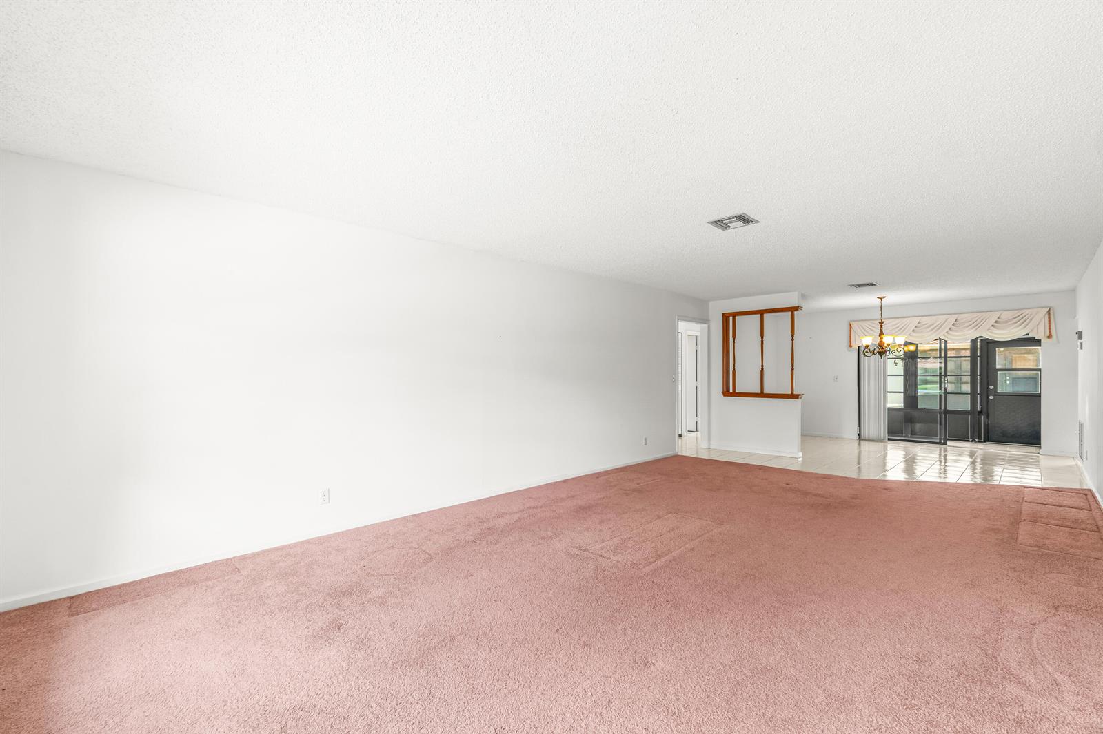 A spacious living room features pink wall-to-wall carpeting, white walls, and a dining area beyond — 4655 Mahoe Tree Place # A, Boynton Beach FL 33436, BOYNTON BEACH, FL