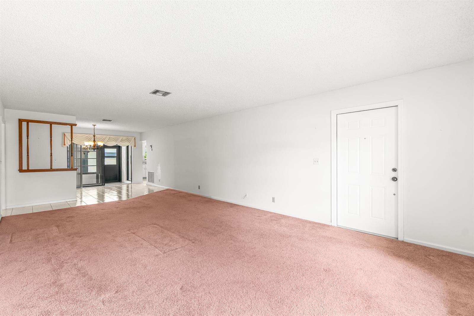 An empty living room features pink carpeting, white walls, and a white front door — 4655 Mahoe Tree Place # A, Boynton Beach FL 33436, BOYNTON BEACH, FL
