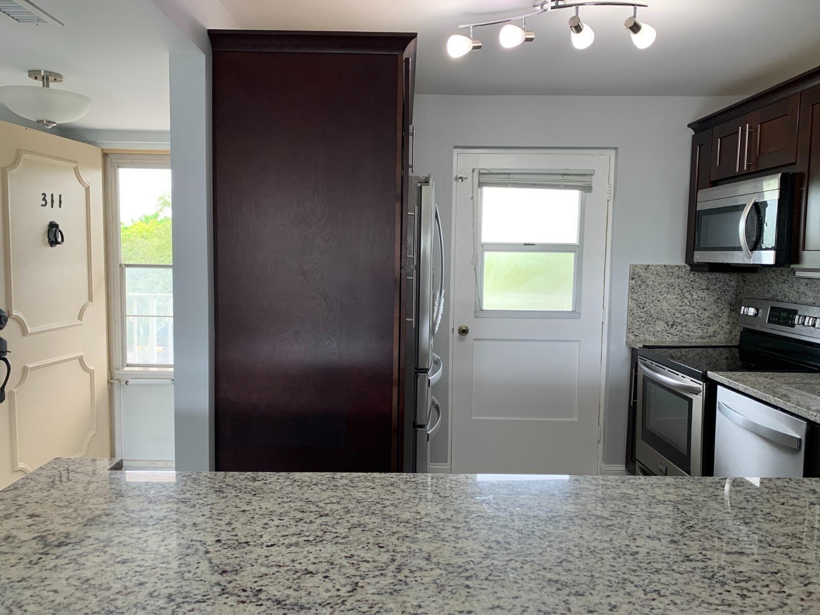 A bright lounge area features two gray leather sofas, a glass coffee table, and mailboxes — 5700 NW 2nd Avenue # 311, Boca Raton FL 33487, BOCA RATON, FL