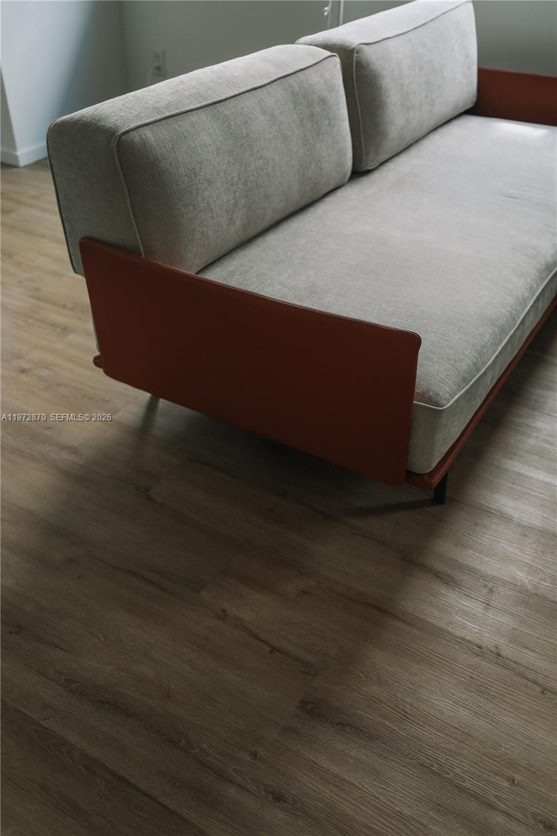 A modern sofa with light gray cushions and a rust-colored frame sits on wood flooring — 128 NE 46th St # 3, Miami FL 33137, MIAMI, FL
