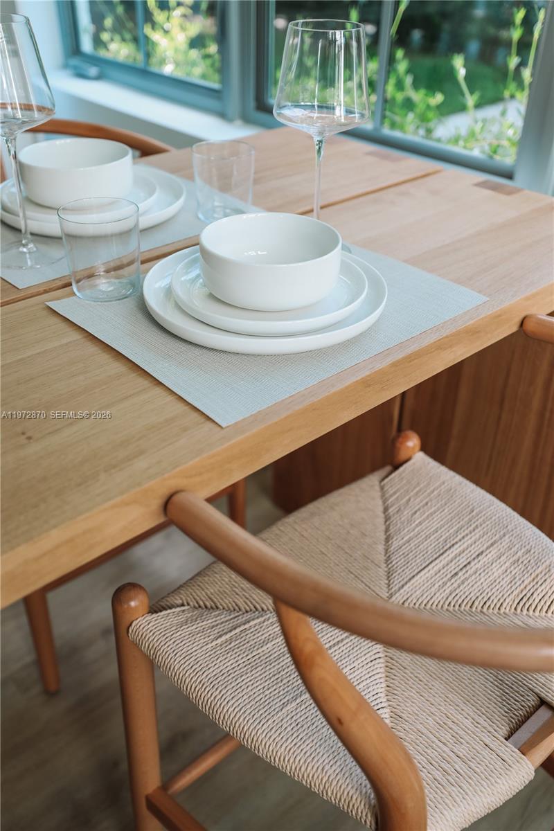 A wooden dining table is set with white dishes and chairs with woven seats — 128 NE 46th St # 3, Miami FL 33137, MIAMI, FL