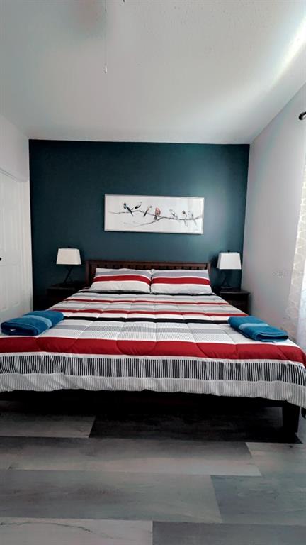 A bedroom features a bed with a striped comforter, dark accent wall, and two bedside lamps — 1138 KNOLLWOOD DRIVE, DAVENPORT, FL
