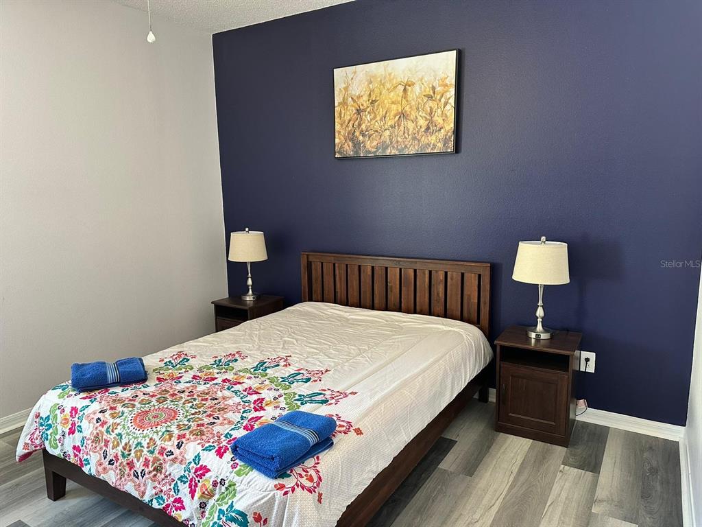 A bedroom features a bed with a floral quilt, two nightstands, and a dark blue wall — 1138 KNOLLWOOD DRIVE, DAVENPORT, FL