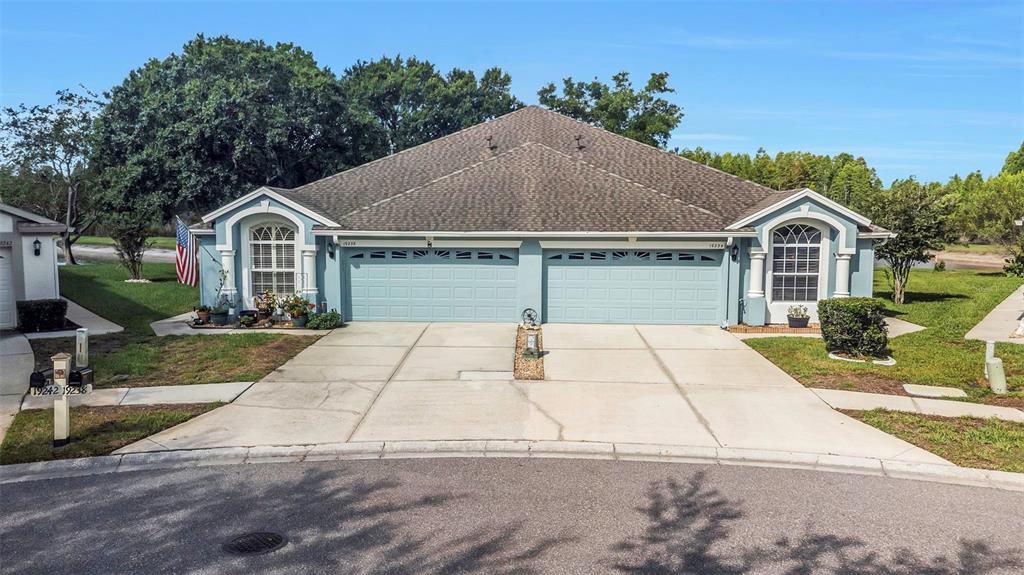 A duplex with light blue siding, two garage doors, and a shared concrete driveway — 19238 WEYMOUTH DRIVE, LAND O LAKES, FL