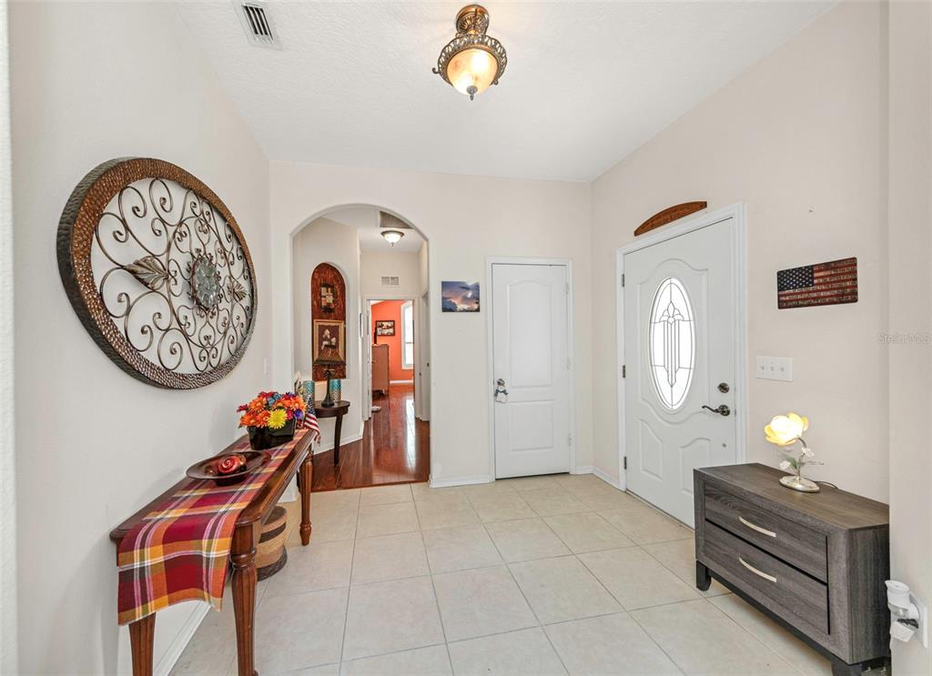 A tiled entryway features a console table, a dark wood chest, and an arched hallway — 19238 WEYMOUTH DRIVE, LAND O LAKES, FL