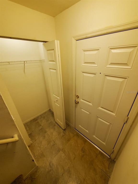 An entryway features a white door, a small closet with a wire shelf, and flooring — 5903 WILLOW RIDGE DRIVE UNIT 203, ZEPHYRHILLS, FL
